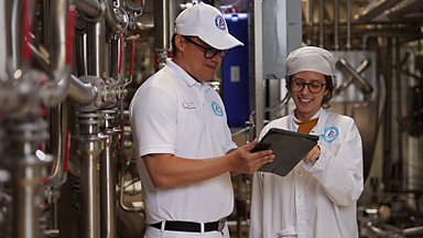 Two Tetra Pak specialists reviewing results on a tablet beside pilot plant equipment