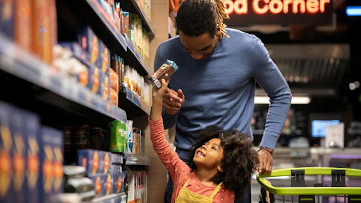 A parent and child choosing a product together in a supermarket aisle