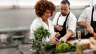 A chef and a food developer preparing greens together in a test kitchen