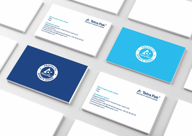 Tetra Pak business cards: white front with bright-blue contact details and dark-blue/light-blue backs bearing the 'PROTECTS WHAT'S GOOD' circular emblem